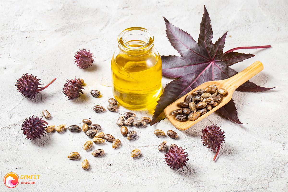 روغن کرچک در یک بطری شیشه ای و دانه و برگ کرچک در کنارش