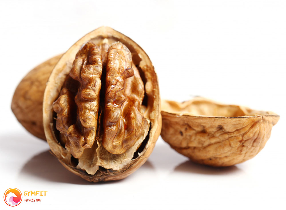 یک گردو نیمه پوست کنده در نمای نزدیک و پس زمینه سفید