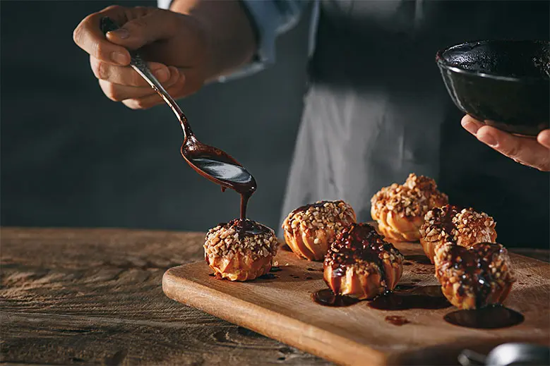 decorating-delicious-homemade-eclairs-with-chocolate-peanuts